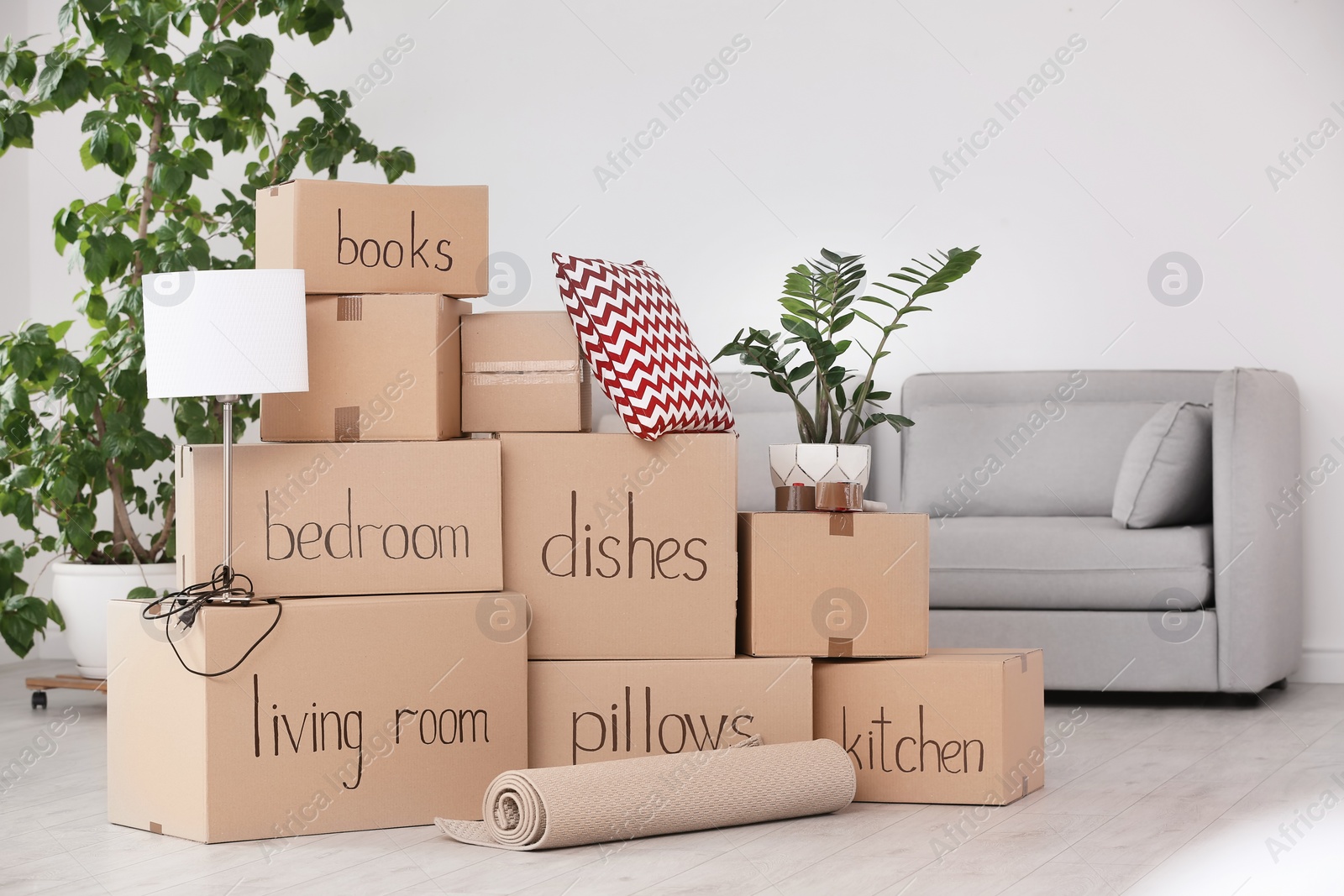 Photo of Pile of moving boxes and household stuff in living room