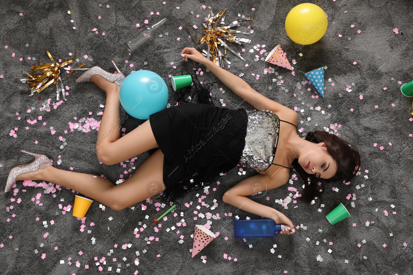 Photo of Drunk young woman sleeping on messy floor after party, top view