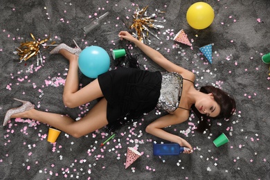 Drunk young woman sleeping on messy floor after party, top view