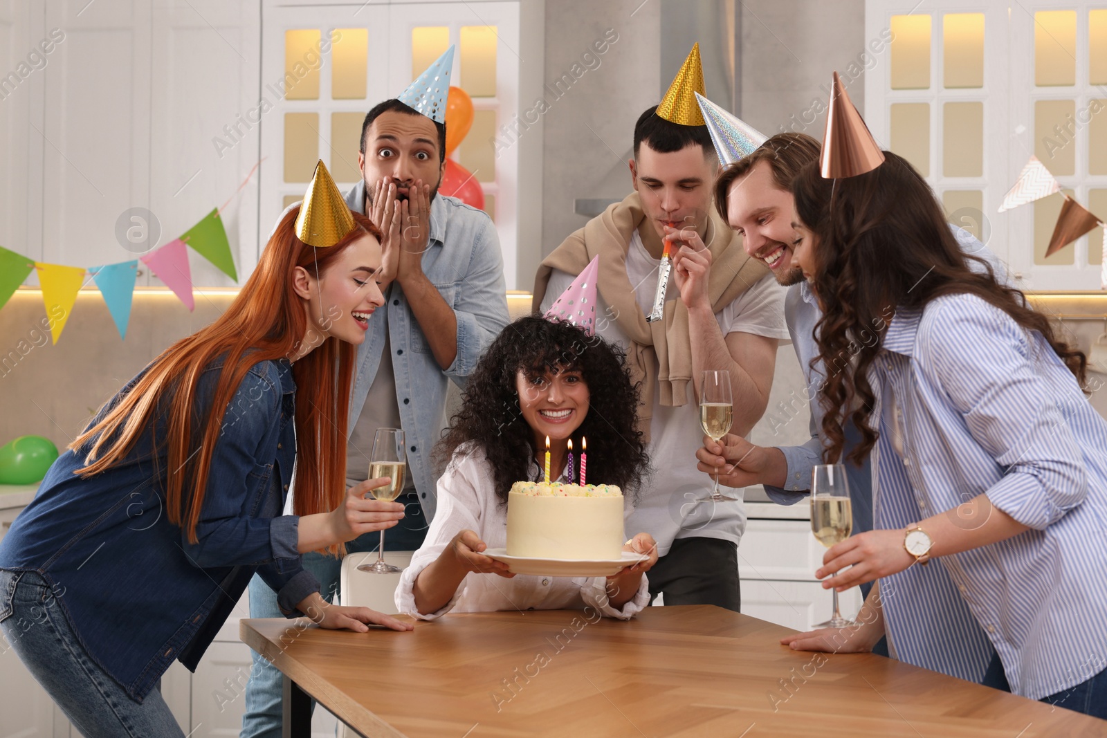 Photo of Happy friends with tasty cake celebrating birthday in kitchen