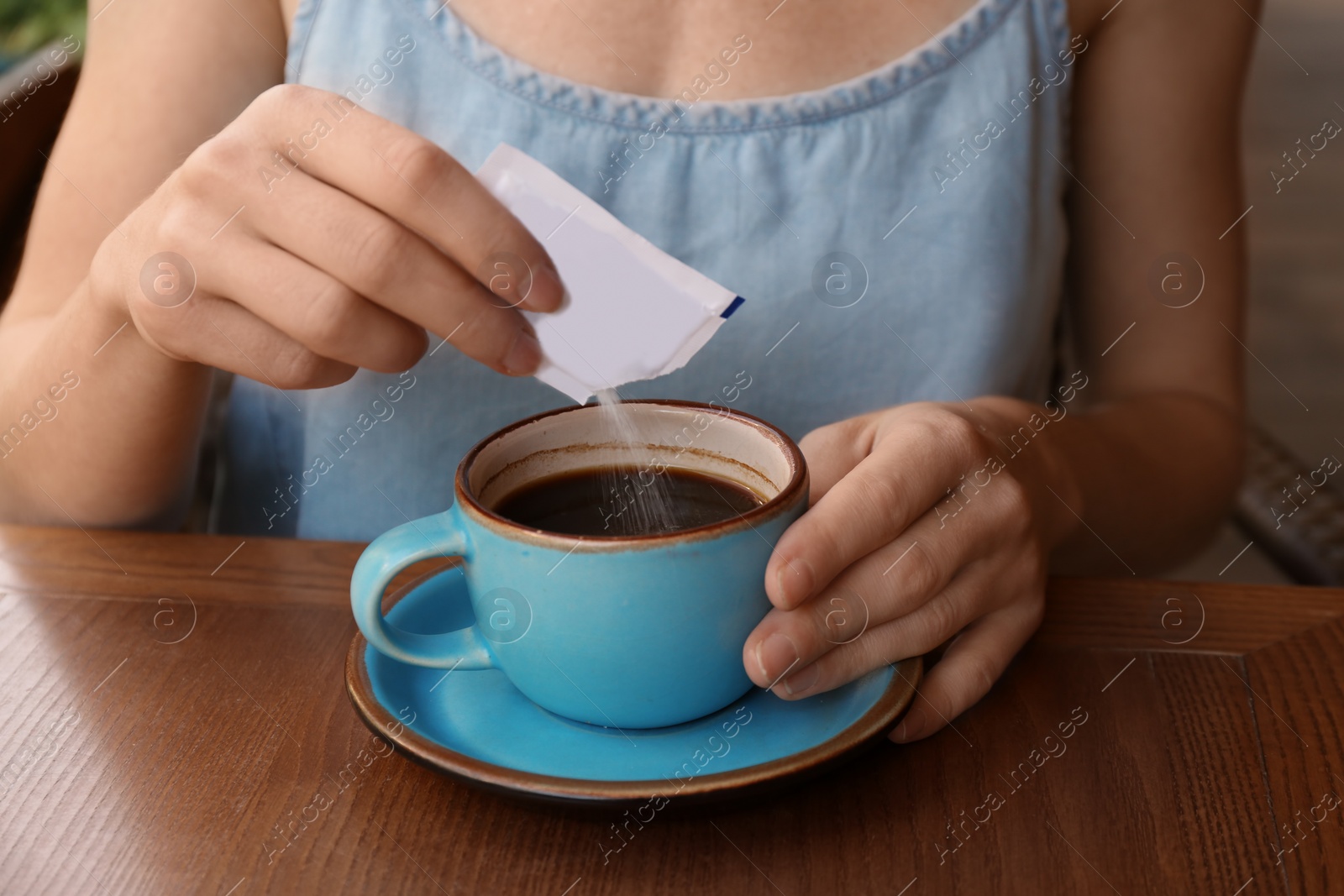 Photo of Woman adding sugar to fresh aromatic coffee at table, closeup