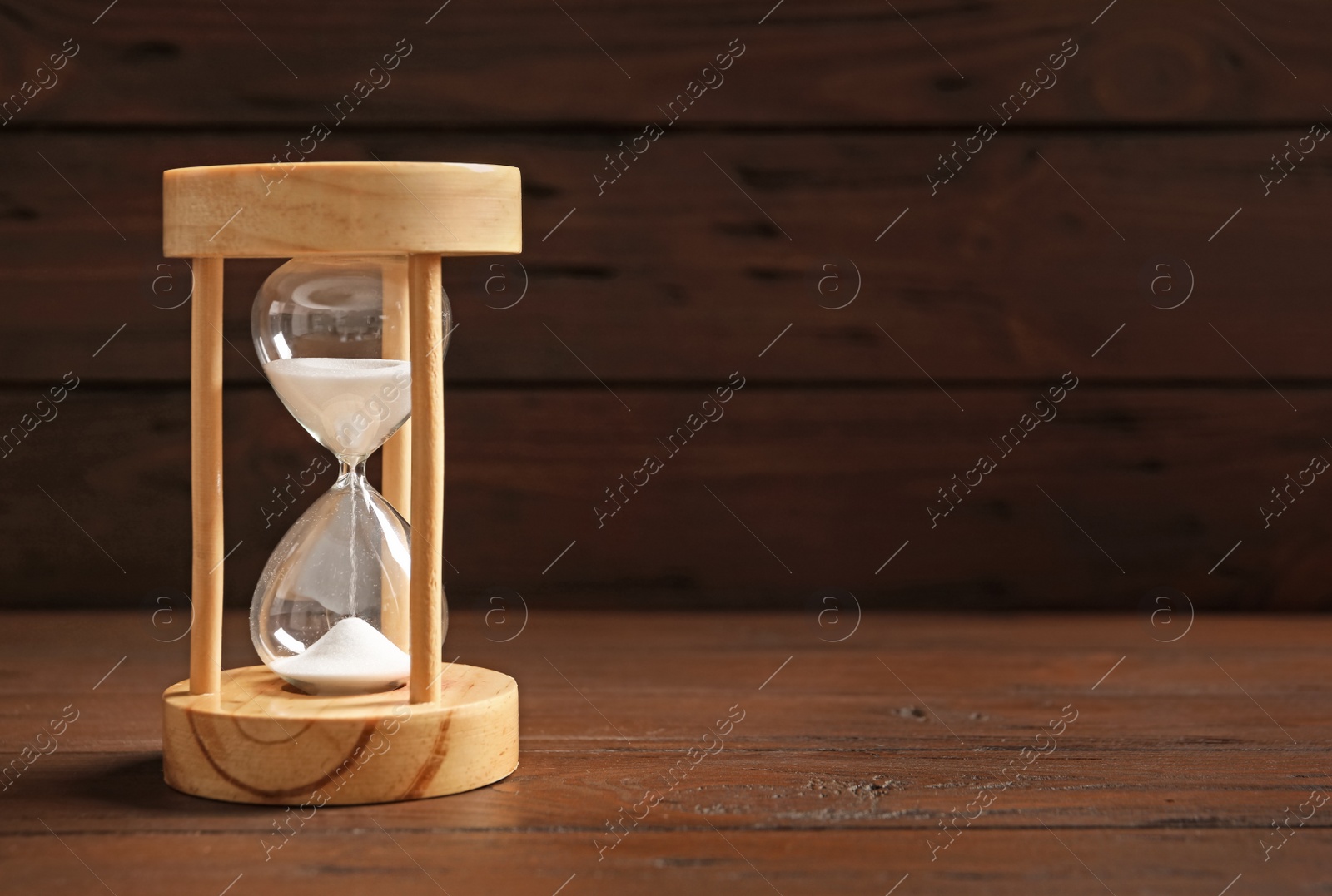 Photo of Hourglass with flowing sand on table against black background. Time management