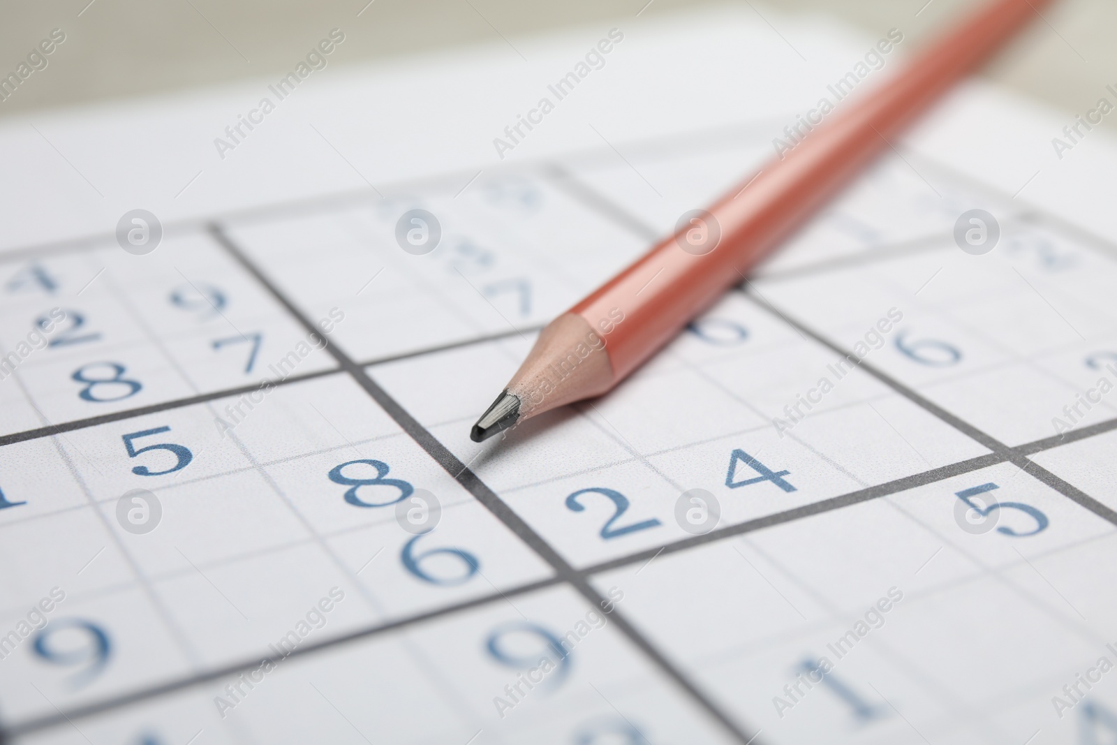 Photo of Sudoku puzzle grid and pencil, closeup view