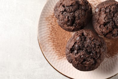 Photo of Delicious chocolate muffins and cacao powder on light grey table, top view. Space for text