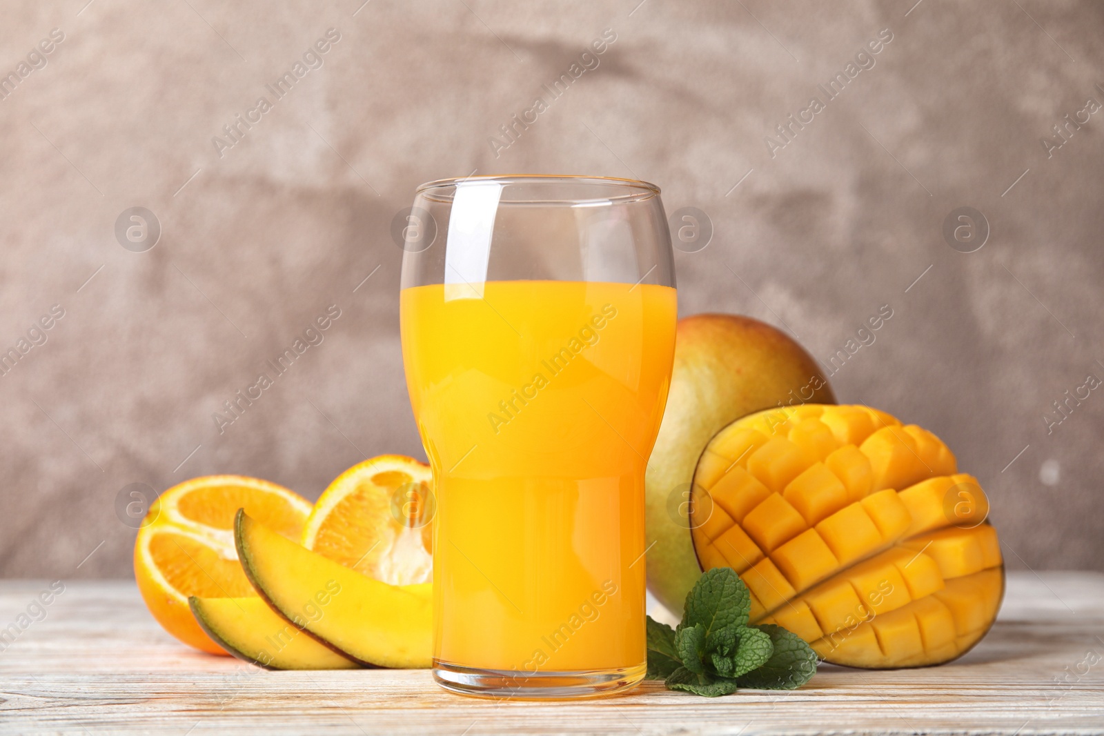 Photo of Glass with fresh mango juice and tasty fruits on wooden table