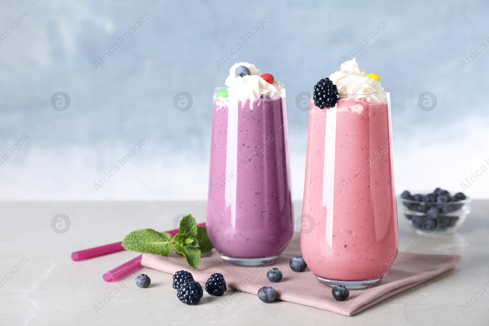 Photo of Tasty milk shakes with toppings on table against blue background