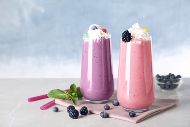 Tasty milk shakes with toppings on table against blue background