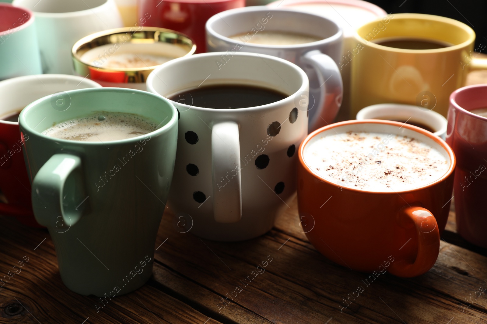 Photo of Many cups of different coffees on wooden table, closeup