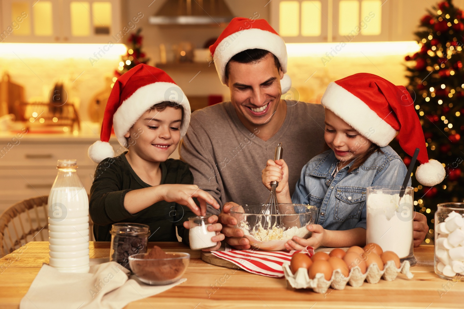 Photo of Happy father and his children making dough for delicious Christmas cookies at home