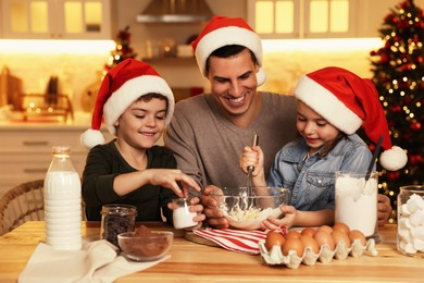 Happy father and his children making dough for delicious Christmas cookies at home