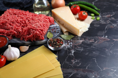 Fresh ingredients for lasagna on black marble table