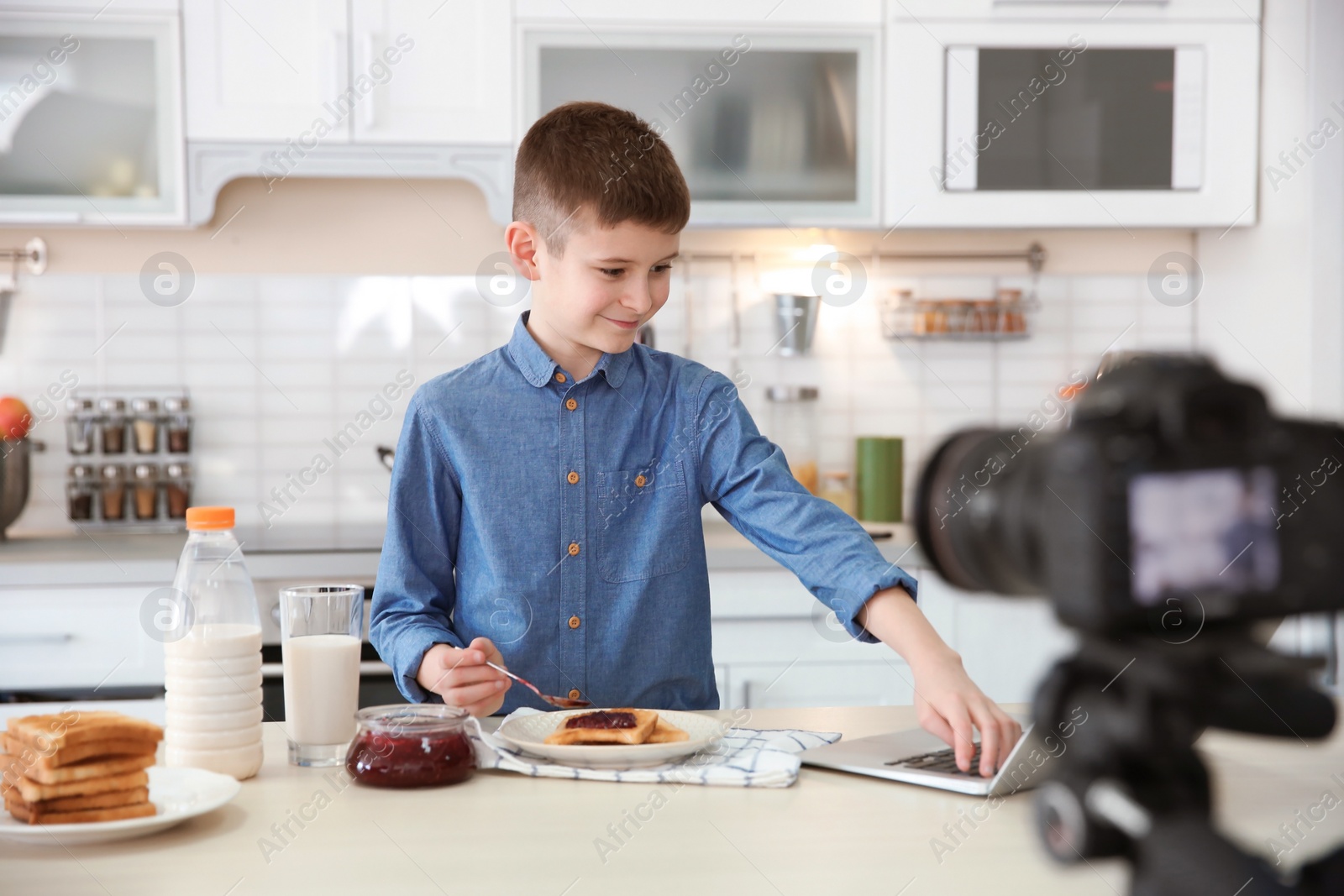 Photo of Cute little blogger with food recording video on kitchen