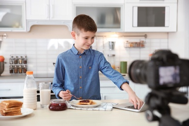 Cute little blogger with food recording video on kitchen