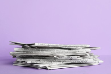 Photo of Stack of newspapers on light violet background, space for text. Journalist's work