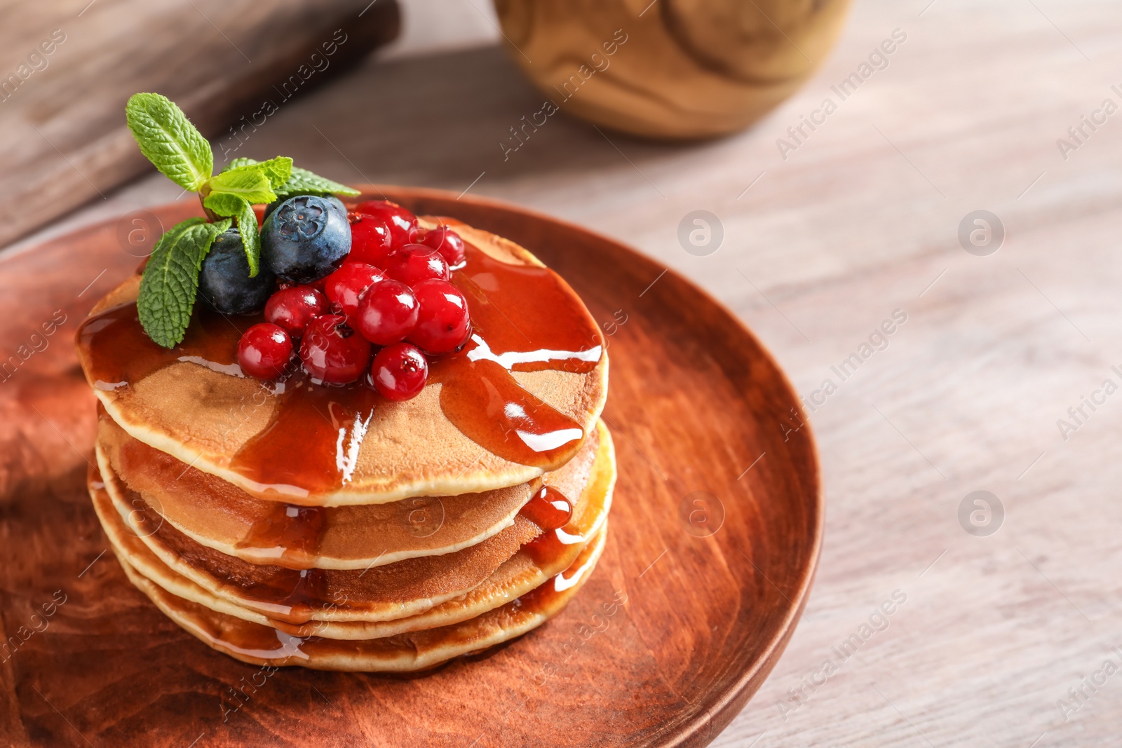 Photo of Stack of tasty pancakes with berries and syrup on table