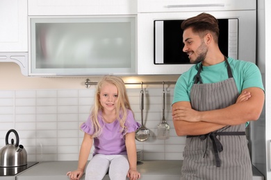 Photo of Young man and his daughter near microwave oven in kitchen