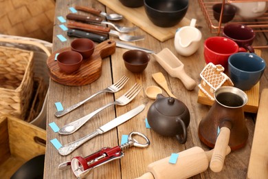 Many different cooking utensils on wooden table. Garage sale