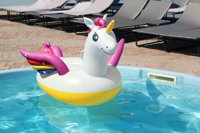 Funny inflatable unicorn ring floating in swimming pool on sunny day, outdoors