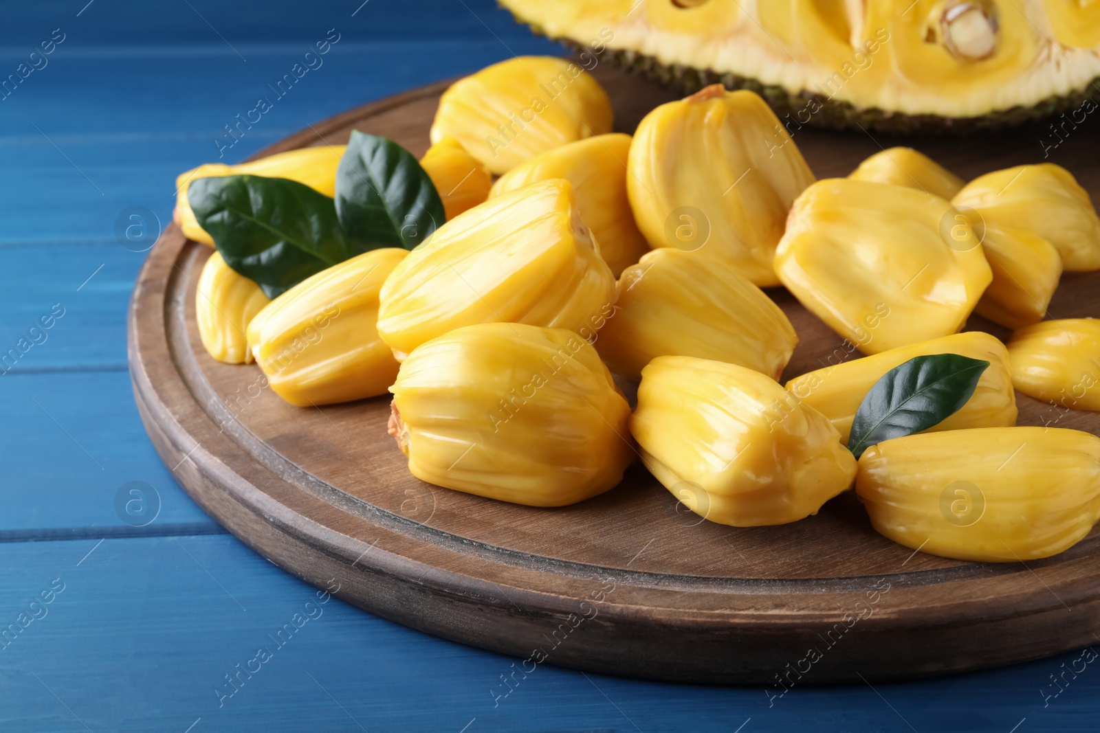 Photo of Delicious exotic jackfruit bulbs on blue wooden table