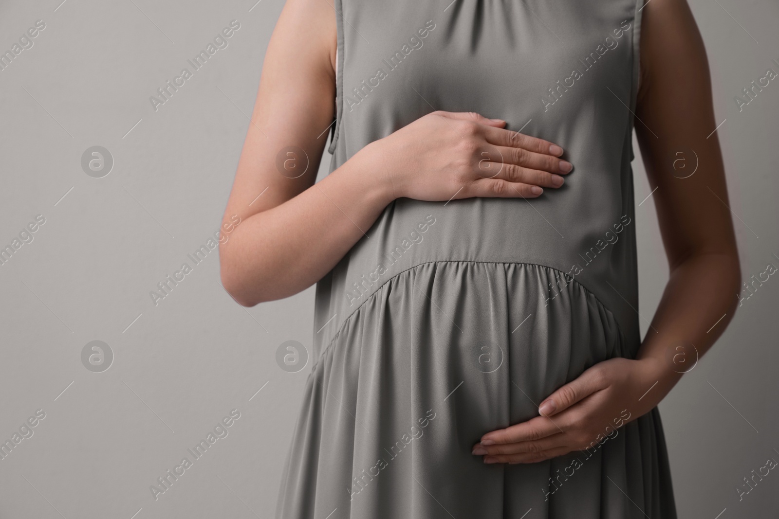 Photo of Pregnant woman on light grey background, closeup