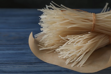 Photo of Raw rice noodles on wooden table, closeup. Space for text