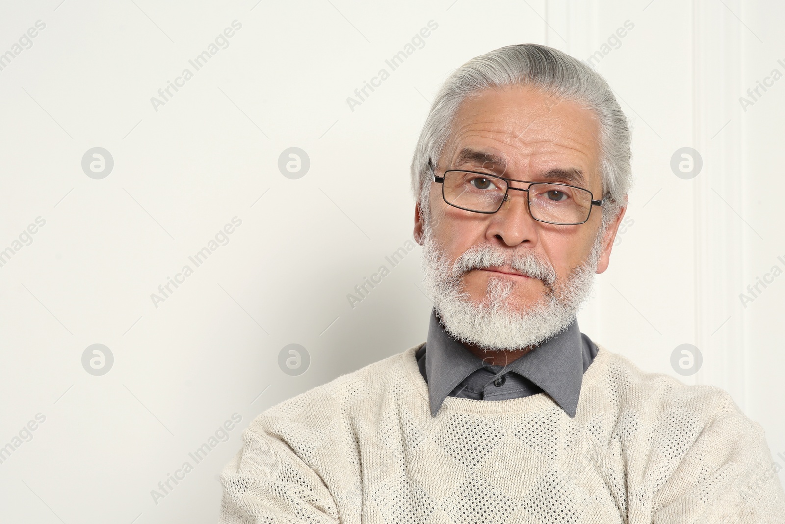 Photo of Portrait of handsome senior man in eyeglasses near white wall. Space for text