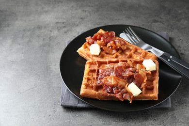 Photo of Tasty Belgian waffles served with bacon and butter on grey table. Space for text