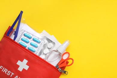 First aid kit on yellow background, top view and space for text