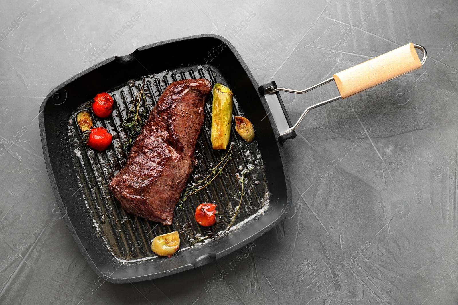 Photo of Delicious grilled beef meat and vegetables in pan on grey table, top view