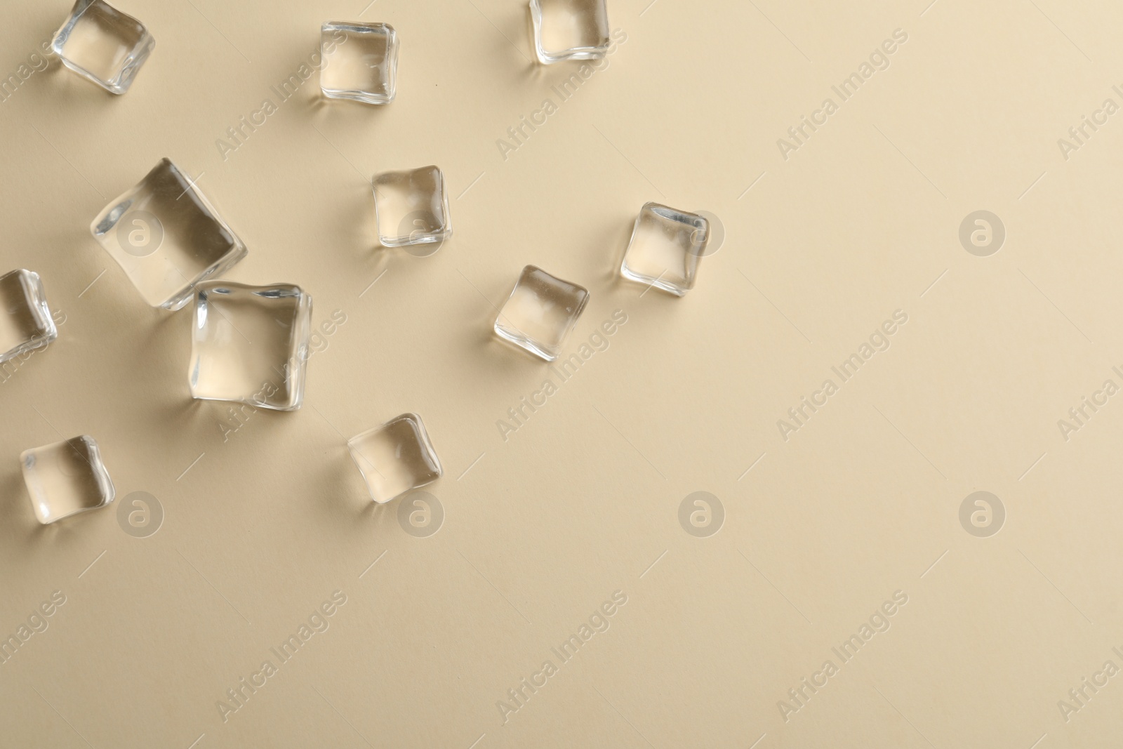 Photo of Crystal clear ice cubes on beige background, flat lay. Space for text