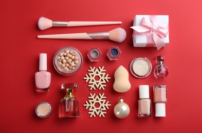 Photo of Flat lay composition with decorative cosmetic products on red background. Winter care