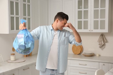 Photo of Man holding full garbage bag at home