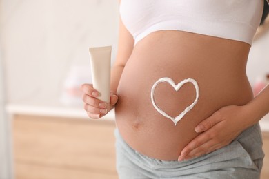 Photo of Young pregnant woman with cosmetic product in bathroom, closeup. Space for text