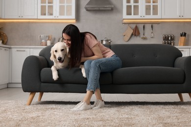 Photo of Woman with cute Labrador Retriever dog on sofa at home. Adorable pet