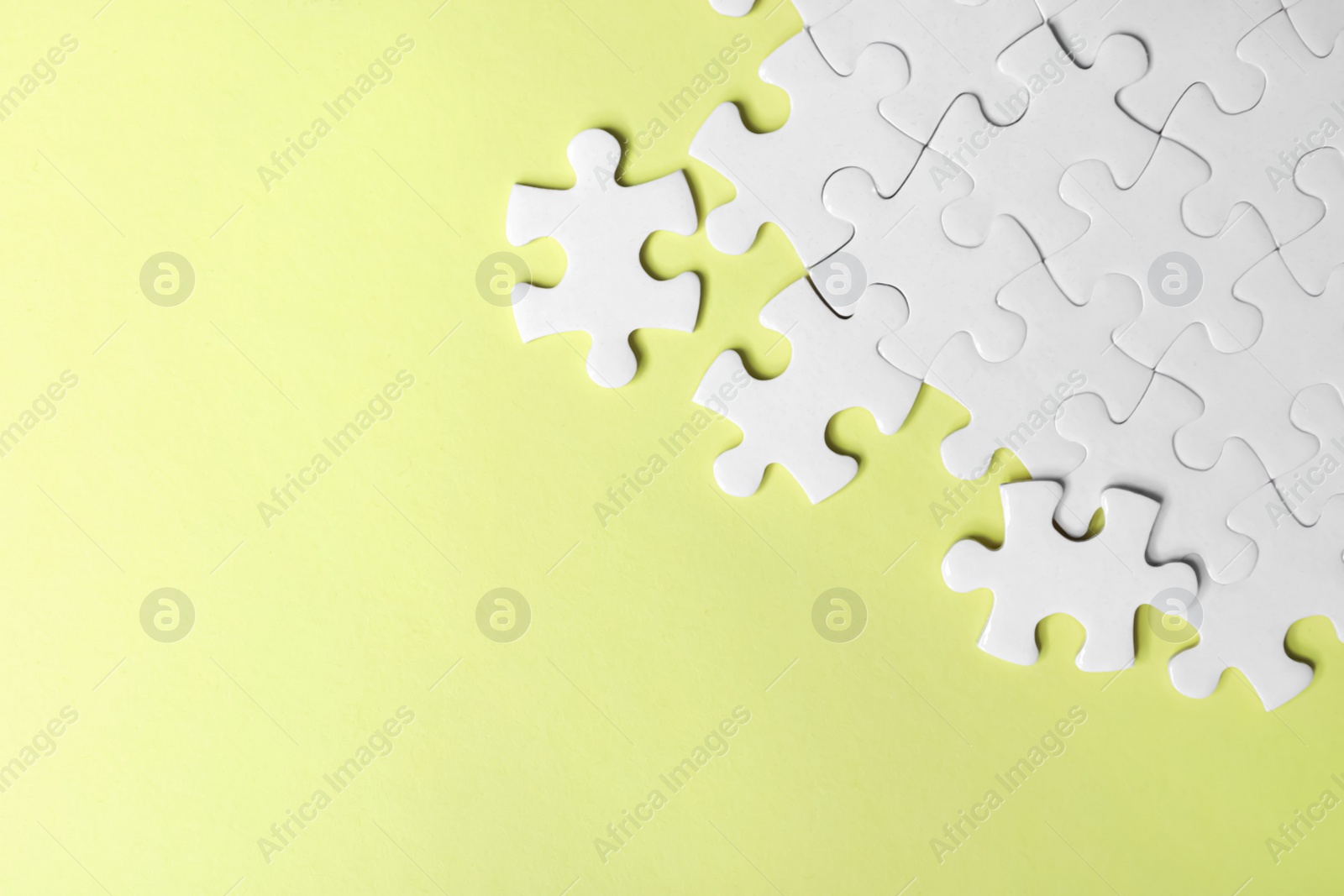Photo of Blank white puzzle pieces on yellow background, flat lay. Space for text