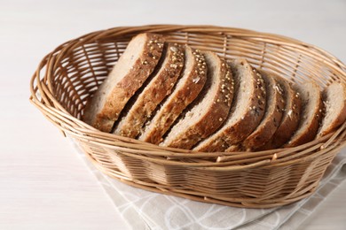 Photo of Slices of fresh homemade bread in wicker basket on white wooden table, closeup