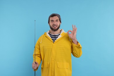 Fisherman with fishing rod showing ok gesture on light blue background