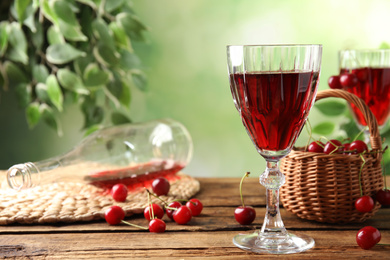 Delicious cherry wine and ripe juicy berries on wooden table. Space for text