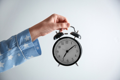 Woman holding alarm clock on white background, closeup. Morning time