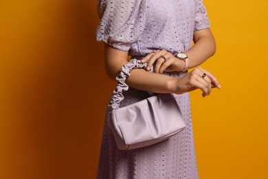 Photo of Fashionable woman with stylish bag on orange background, closeup