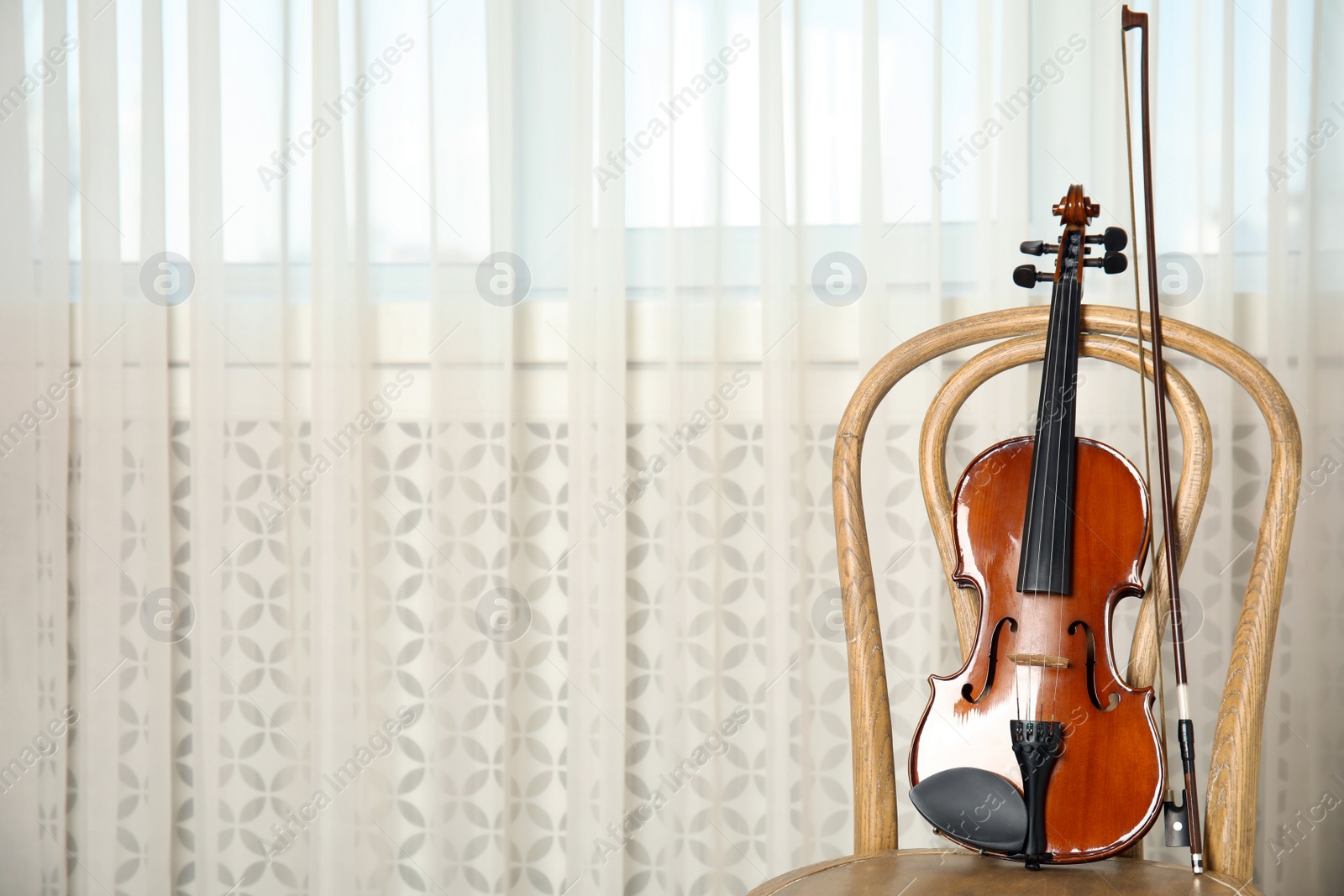 Photo of Classic violin and bow on chair indoors. Space for text