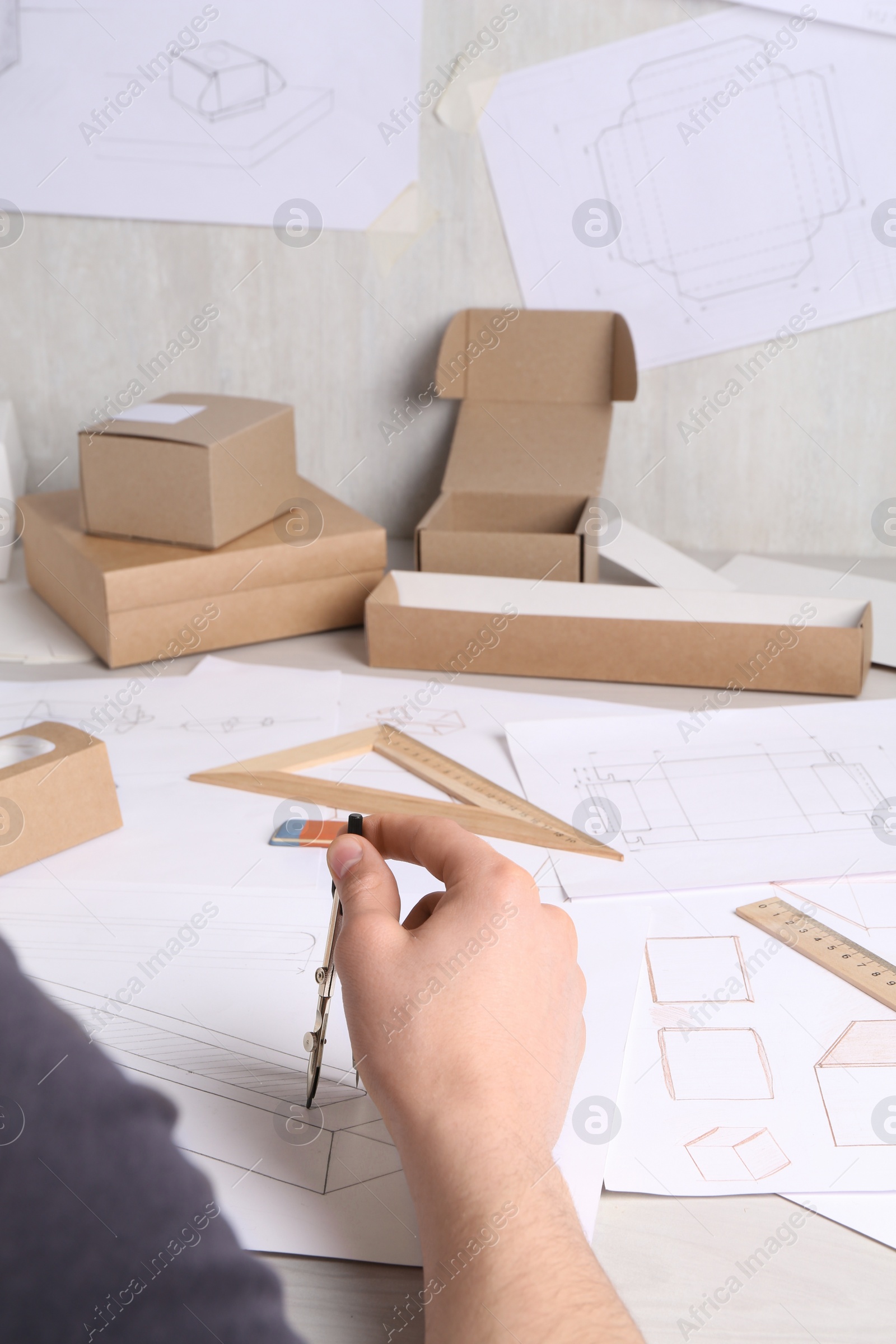 Photo of Man creating packaging design at light wooden table, closeup