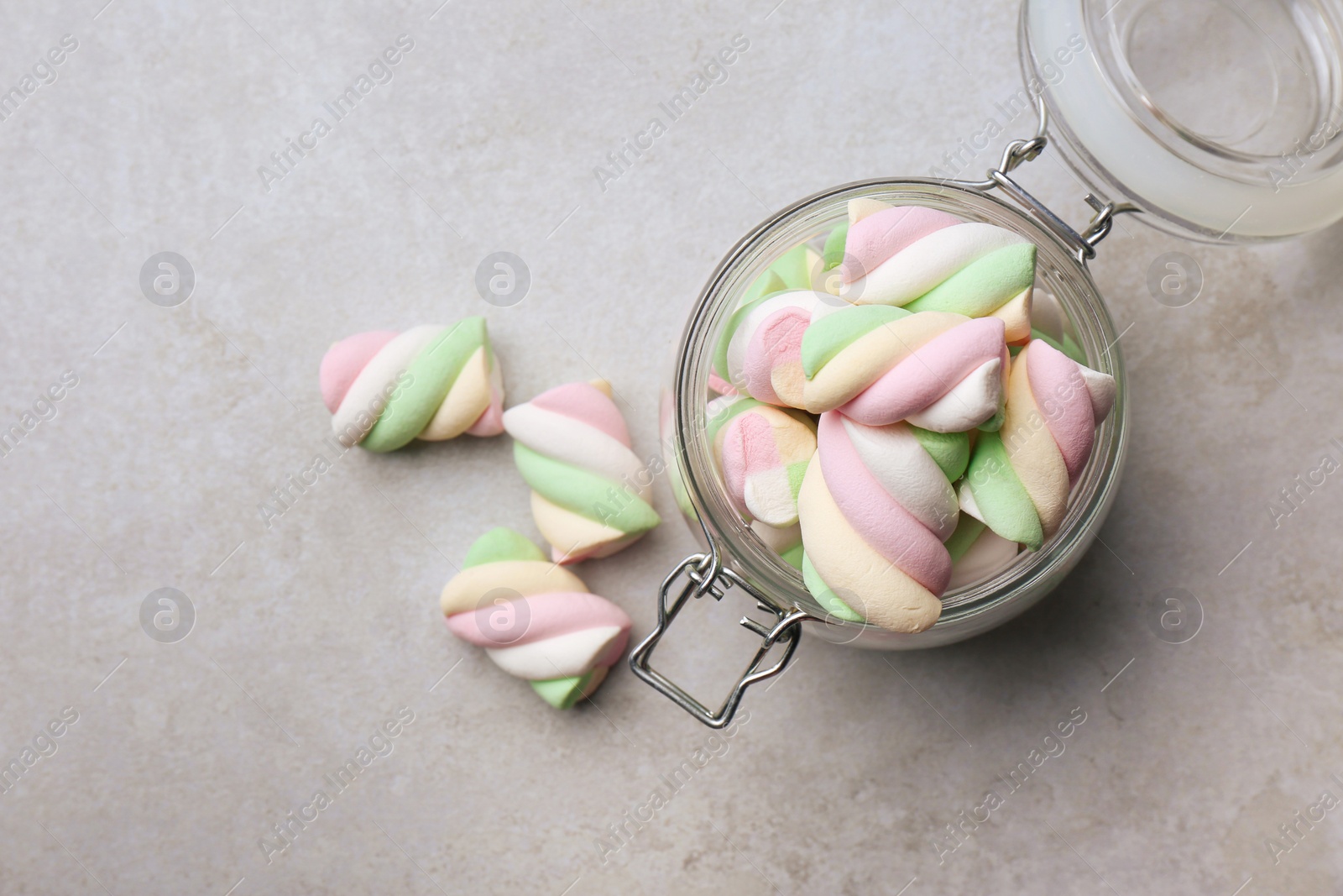 Photo of Glass jar with delicious colorful marshmallows on light grey table, flat lay. Space for text