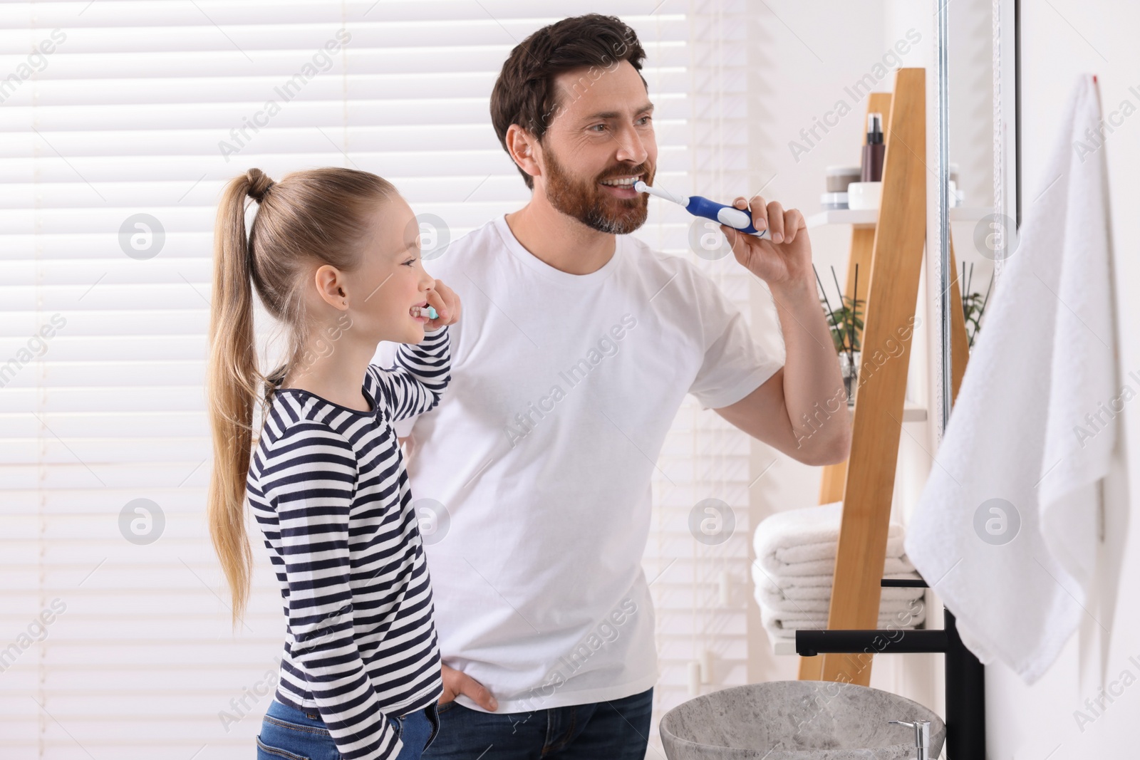 Photo of Father and his daughter brushing teeth together in bathroom