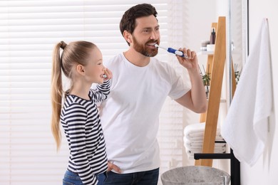 Father and his daughter brushing teeth together in bathroom