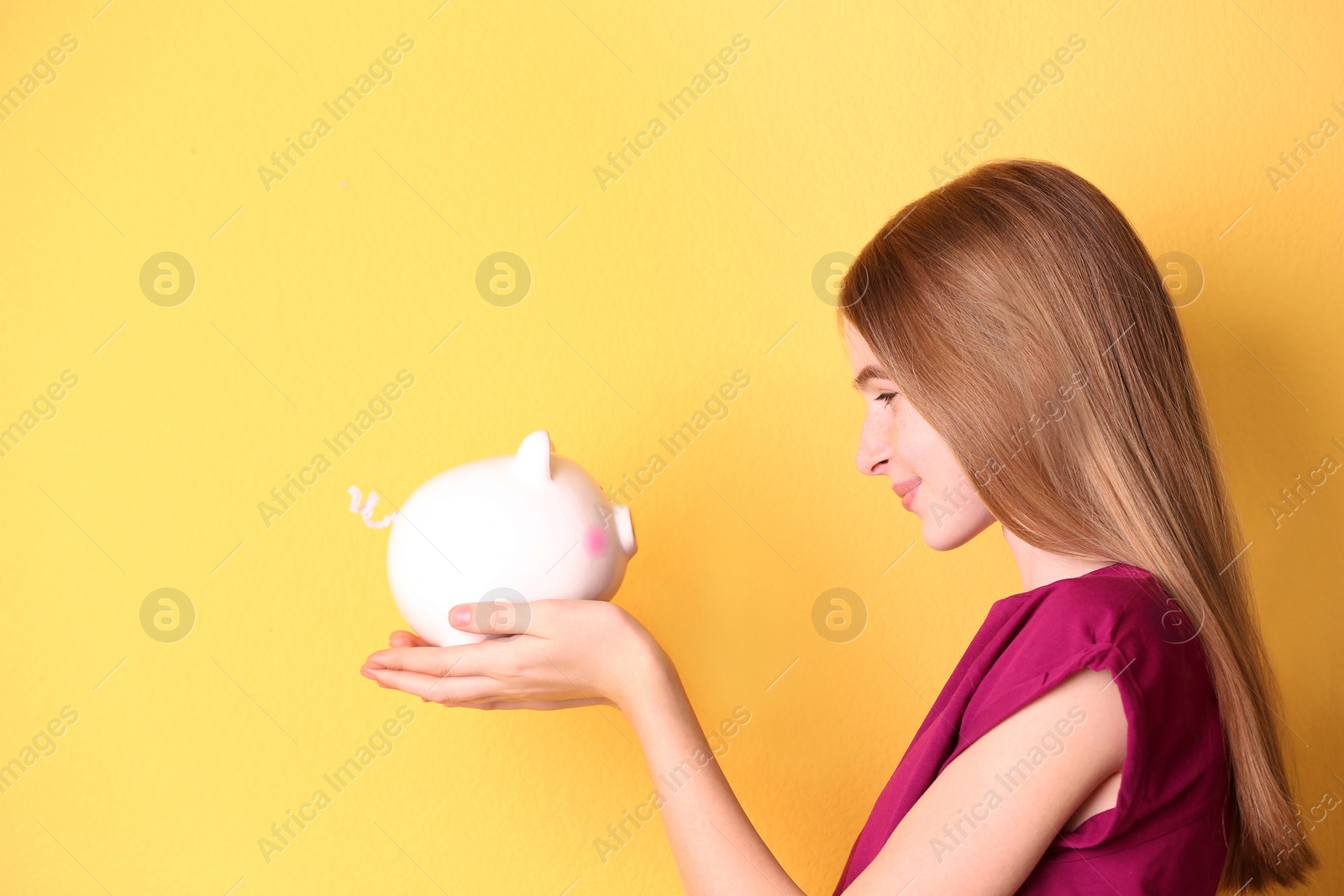 Photo of Teen girl with piggy bank on color background