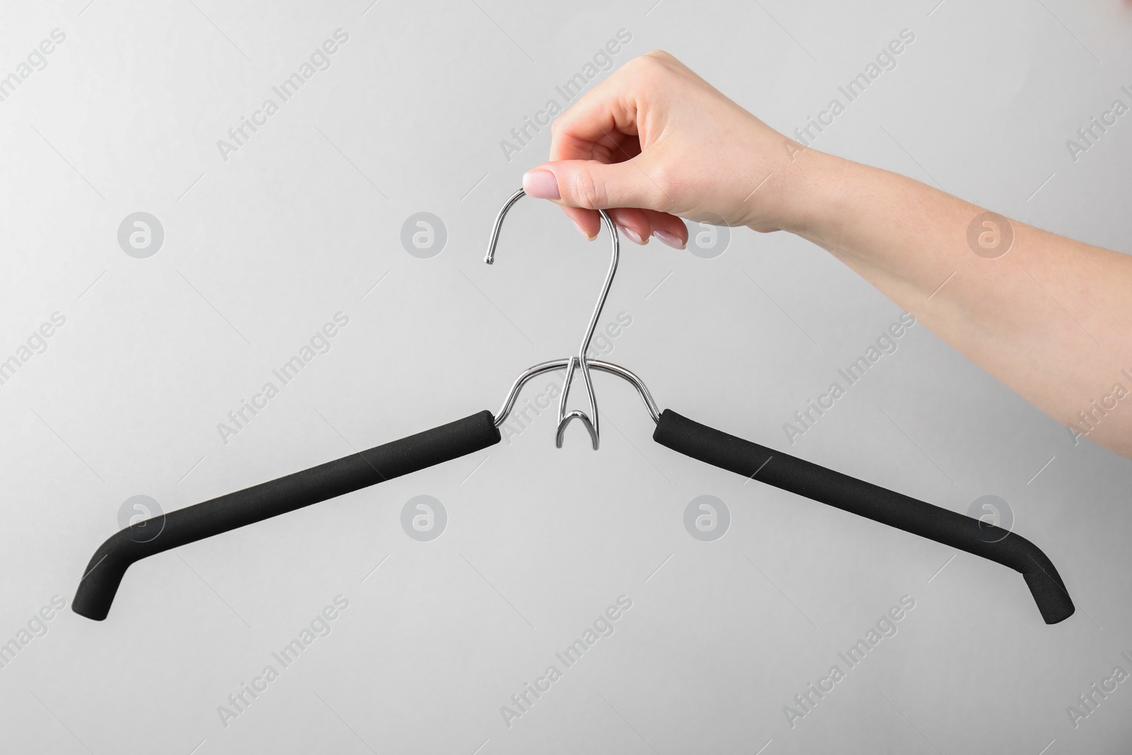 Photo of Woman holding hanger on light grey background, closeup