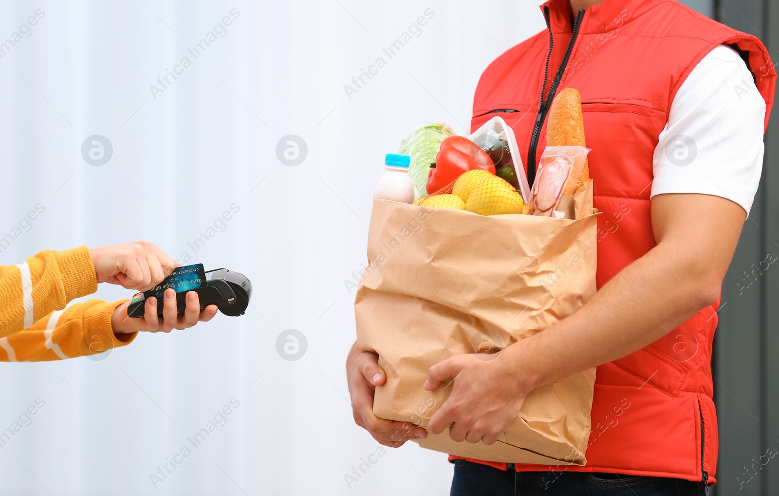 Photo of Woman using terminal to pay for food delivery indoors, closeup