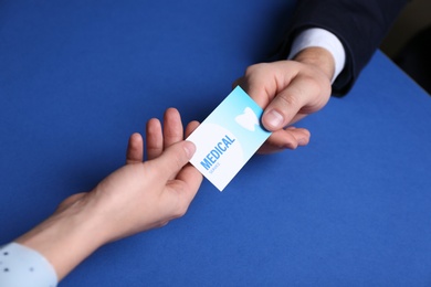 Photo of Man giving business card to woman on color background, closeup. Dental medical service