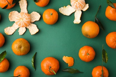 Frame made of many fresh ripe tangerines and leaves on green table, flat lay. Space for text